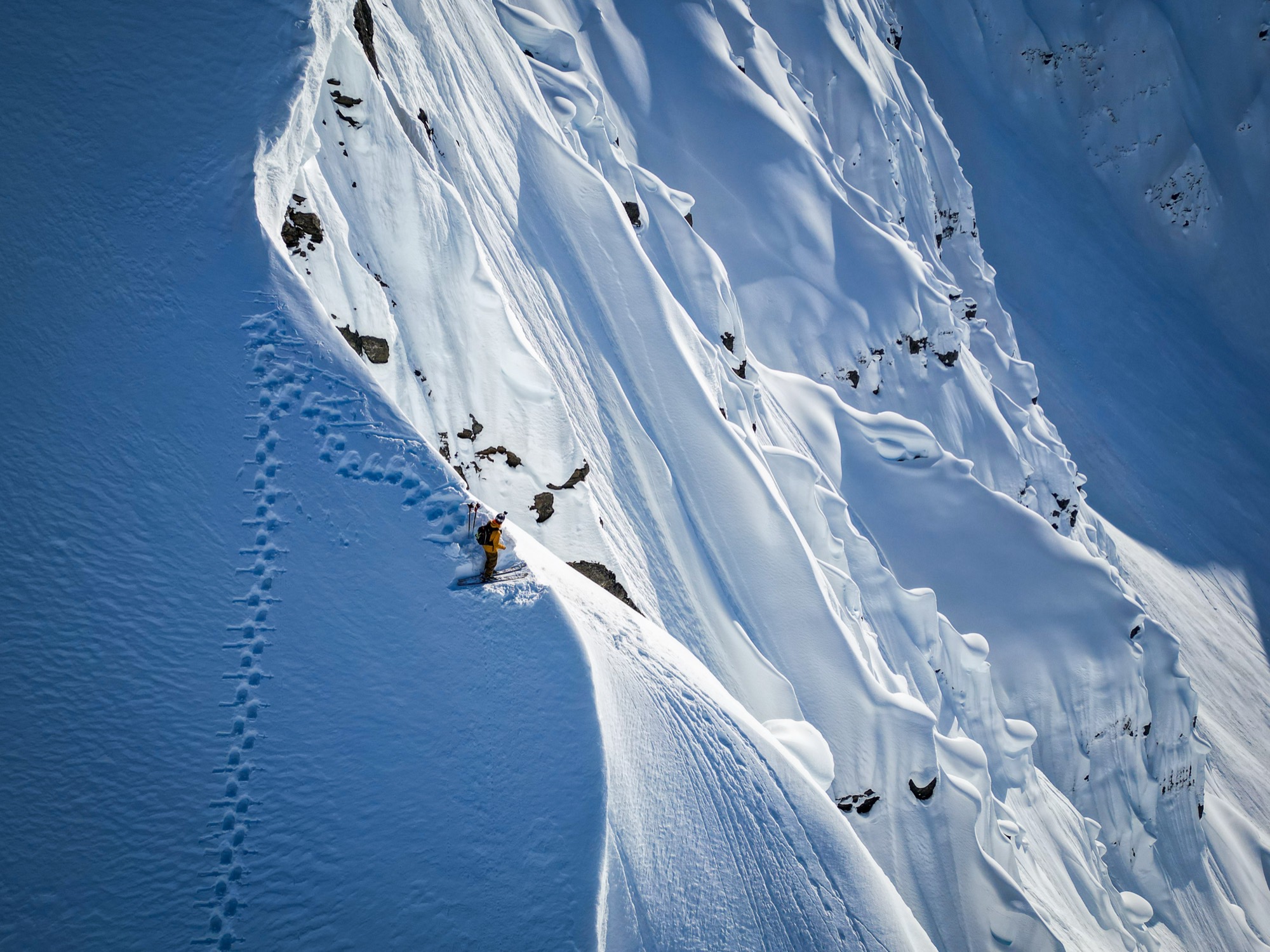 Skier on a steep fluted face above a skin track
